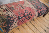 Distressed vintage Oushak rug ottoman fragment, faded red, beige, charcoal geometric patterns.