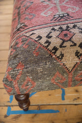 Distressed vintage Oushak fragment wraps ottoman corner, showing faded red, beige, charcoal pattern.