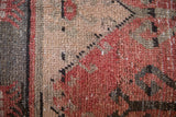 Distressed vintage Turkish Oushak rug fragment pile texture in faded red, beige, charcoal.