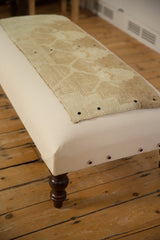 Corner of the canvas ottoman coffee table showing the dark wood leg and side snap detail.
