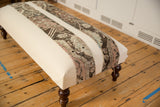 Angled side view of the handmade canvas ottoman with its changeable vintage rug fragment stripes.