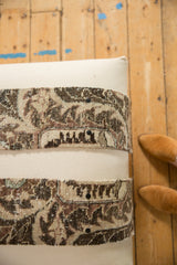 Corner detail of a canvas ottoman with textured, snap-on vintage rug fragment bands.