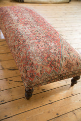 Edge of vintage Persian rug upholstery, showing detailed pattern and dark carved leg.