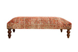 Vintage Persian rug ottoman table with bold multi-color design and turned wooden legs.