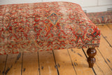 Vintage Persian Rug Ottoman corner, showcasing intricate rusty red, blue, ivory pattern, turned leg.