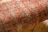 Vintage Persian rug fragment on ottoman, showing isolated wear with muted red, beige, and blue patterns.