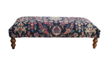 Vintage Persian rug ottoman table with navy floral Yezd fragment and turned wooden legs.