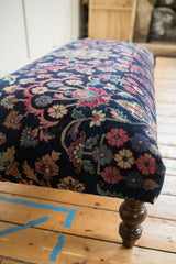 Vintage Yezd rug ottoman: navy field, faded magenta florals, and curved wooden leg.