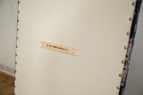 Old New House wooden tag, light canvas backing, and brass studs on ottoman underside.