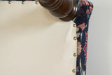 Ottoman underside, featuring cream cotton canvas, brass studs, wooden leg, and vintage Persian rug.