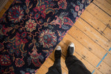 Detailed view of a vintage rug ottoman's navy upholstery with magenta and ivory floral motifs.
