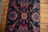 Overhead detail of the Yezd rug's central medallion with magenta and ivory floral motifs.