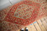 Diagonal segment of vintage Senneh rug: red-orange, sea blue, ivory floral motifs.