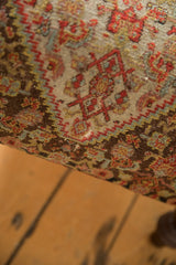 Hand-knotted pile of vintage Persian Senneh rug fragment, showing geometric red, blue, ivory patterns, and wear.