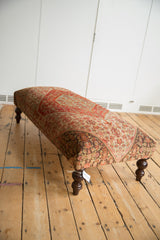 Curved dark turned wooden leg of the vintage Persian rug ottoman.