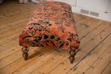Vintage Lilihan hand-knotted fragment with dusty rose floral design and turned leg on ottoman.