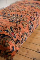Angled close-up of vintage Lilihan rug fragment, dusty rose with botanical motifs and subtle wear.