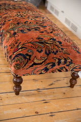 Angled view of vintage Lilihan rug ottoman top, dusty rose and navy curvilinear floral pattern.