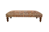 Unique vintage Persian rug ottoman table, intricate pattern in muted colors, curved wooden legs.