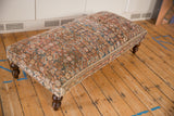Vintage Persian rug ottoman side with aged allover pattern in soft red, blue, cream, and dark turned leg.