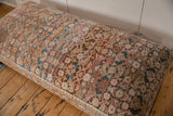Close-up of vintage Persian rug fragment with muted terracotta, blue, and cream patterns.