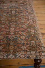 Intricate pattern of vintage Persian rug fragment on ottoman, showing soft terracotta, blue, and aged texture.