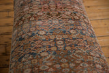 Faded blue, rust, and beige intricate pattern on worn vintage Persian rug fragment.