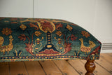 Detailed view of an antique rug ottoman showing a pictorial chicken in sand and red on a rich sapphire blue field.