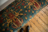 Angled detail of the ottoman's antique Persian rug top with floral motifs.