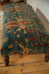 Side profile of a reclaimed rug ottoman showing detailed floral patterns in sapphire, red, and sand.