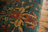 Close-up on the antique Persian rug upholstery with cochineal red and sand floral motifs over a sapphire blue field.