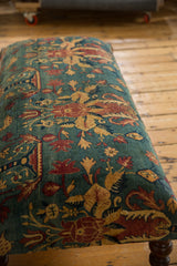 Close view of the antique rug ottoman's surface, detailing the sheen on its floral pattern.