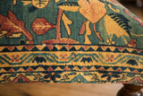Close-up of the antique rug ottoman's upholstery showing pictorial motifs and a geometric border.