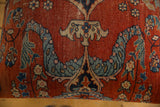 Close-up of the antique Persian rug's woven texture with a blue, ivory, and red floral palmette design.