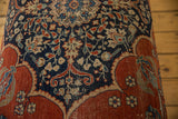 Close-up of the antique Persian rug ottoman showing intricate floral motifs in navy, red, and ivory.