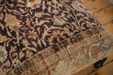 Detailed view of the vintage Persian rug ottoman corner with textured, low-pile wear.
