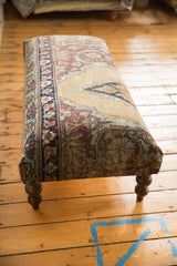 Intricate border and floral design of antique Persian Kerman rug on ottoman with carved leg.