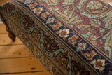 Antique Persian Kerman ottoman detail: deep blue border, traditional floral motifs, and rich patina.