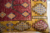 Textured geometric Oushak pillow pattern in deep red, golden yellow, and blue tones.