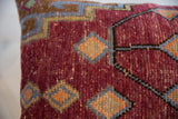 Textured vintage Oushak rug fragment pillow with vibrant red, blue, and orange geometric patterns.