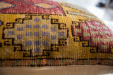 Detailed knotting of vintage Oushak rug fragment pillow with mustard, red, and blue patterns.