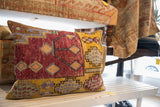 Vintage Oushak pillow side with yellow, maroon, and blue geometric rug fragment design.