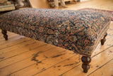 Dark turned wooden leg and antique Persian Fereghan rug fragment detail.