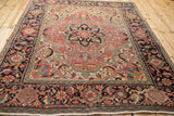A perspective view of a vintage Heriz rug's ornate medallion and Samovar design border in ruby and navy.