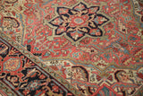 Ornate floral vinery and serrated leaves in ruby red and navy on a vintage hand-knotted Heriz rug.