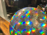 Holographic globe surface with vibrant rainbow light patterns and visible continents.
