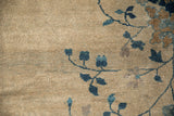 Speckled antique ivory field of a Peking carpet, with deep sapphire blue and copper brown botanical motifs.