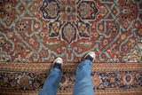 Hand-knotted Heriz carpet with bold geometric pattern in brick red, navy, and gold, visible underfoot.