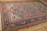 Vintage Heriz carpet corner showcasing bold geometric outlines in navy, brick red, ivory.