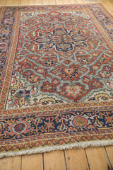Heriz rug with brick red, navy, ivory geometric patterns, scalloped contours, and fringe.